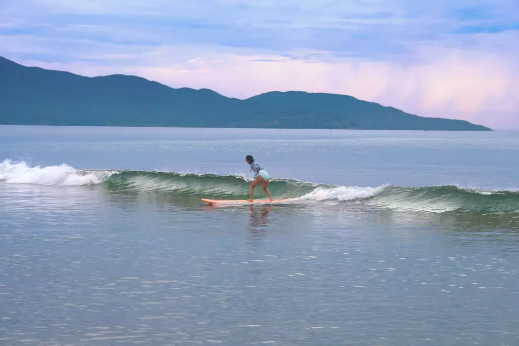A woman riding a small wave on a surfboard in Da Nang