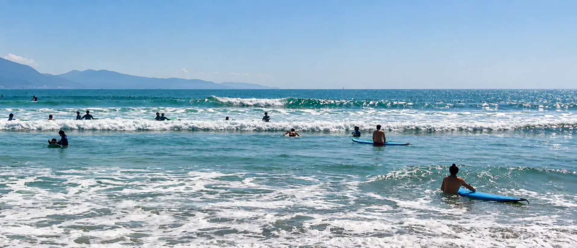 Surfers and swimmers near the shorebreak at a beach in Da Nang